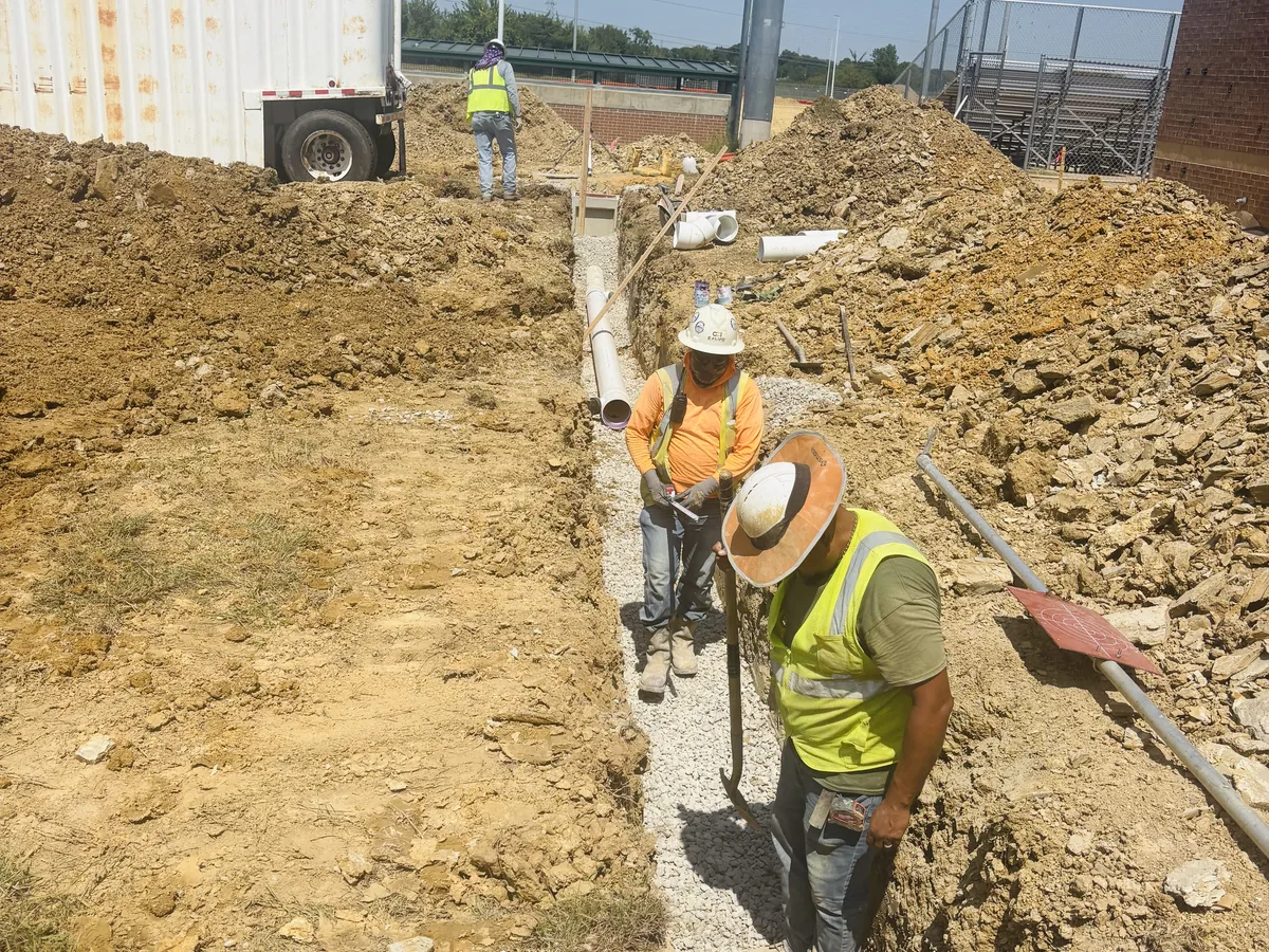Worker compacting backfill in a trench
